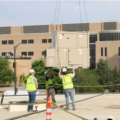 workers helping lower a rooftop unit